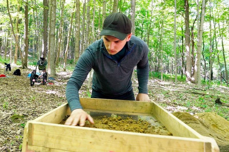 一个大学生在树林里的考古挖掘中工作